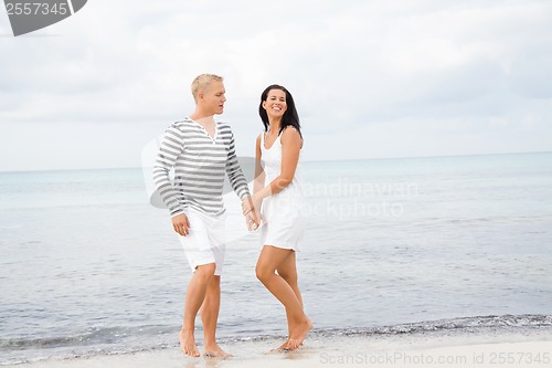 Image of Couple holding hands while walking on the beach