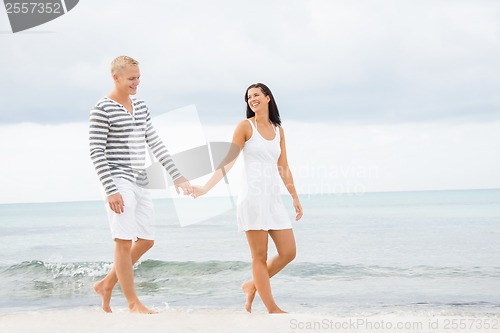 Image of Couple holding hands while walking on the beach