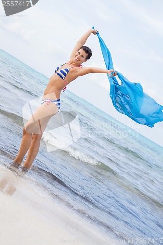 Image of Carefree woman on a beach with a floating scarf