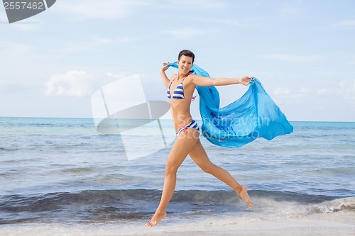 Image of Carefree woman on a beach with a floating scarf