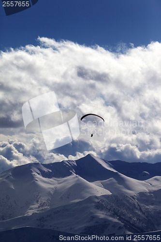 Image of Winter mountains in evening and silhouette of paraglider