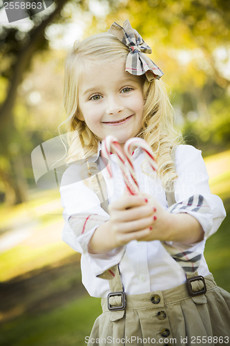 Image of Cute Little Girl Holding Christmas Candy Canes Outdoors
