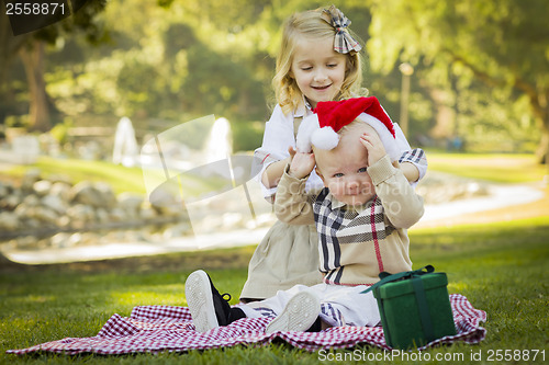 Image of Little Girl Tries to Put Santa Hat on Baby Brother
