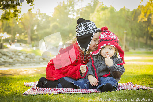 Image of Little Girl Whispers A Secret to Baby Brother Outdoors