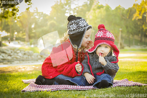 Image of Little Girl Whispers A Secret to Baby Brother Outdoors