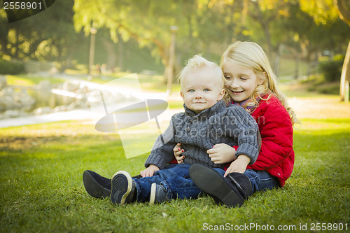 Image of Little Girl with Baby Brother Wearing Coats at the Park
