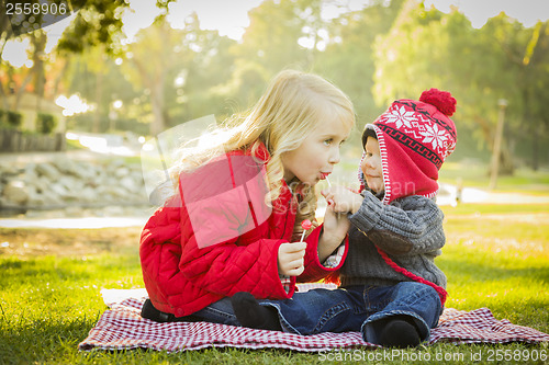 Image of Little Girl with Baby Brother Wearing Coats and Hats Outdoors
