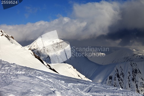 Image of Off-piste slope and sunlit mountains in clouds