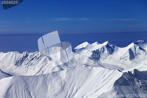 Image of Off-piste snowy slope at sunny day and multicolor blue sky