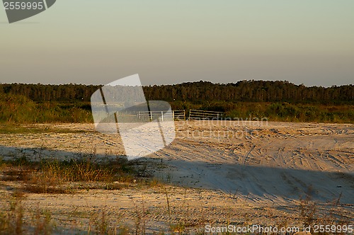 Image of end of dirt road blocked by gate at sunset