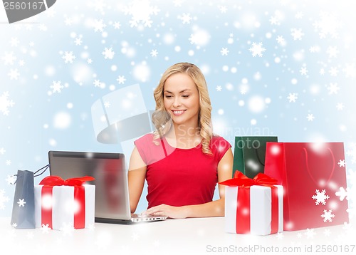 Image of woman with gift boxes, bags and laptop computer