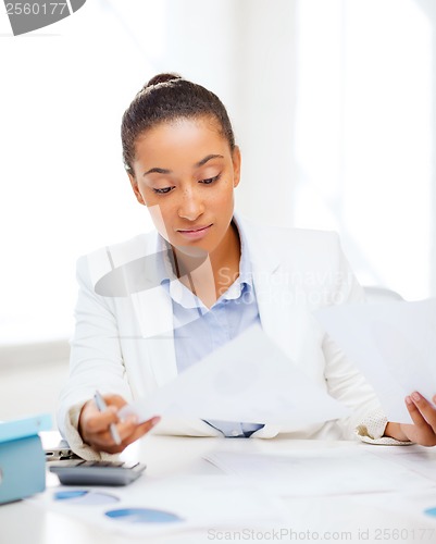 Image of businesswoman working with calculator in office