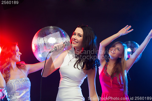 Image of three smiling women dancing and singing karaoke