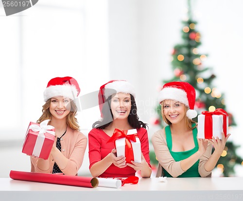 Image of smiling women in santa helper hats with gift boxes