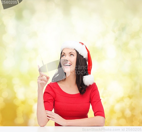 Image of woman in santa helper hat pointing to something