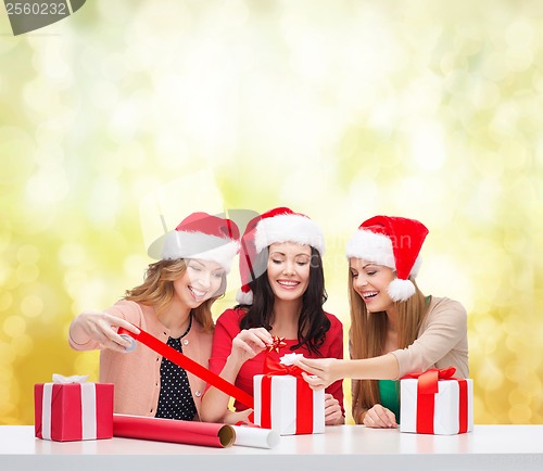 Image of smiling women in santa helper hats with gift boxes