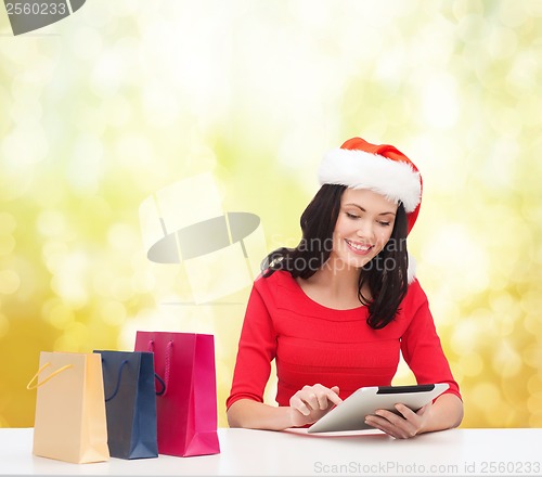 Image of smiling woman with shopping bags and tablet pc