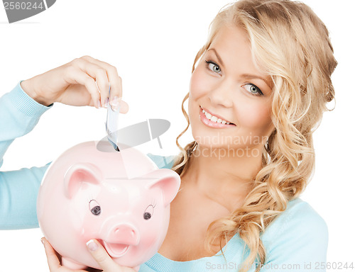 Image of woman puts cash money into big piggy bank