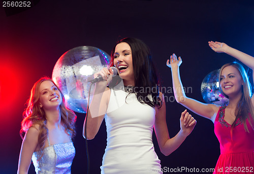 Image of three smiling women dancing and singing karaoke