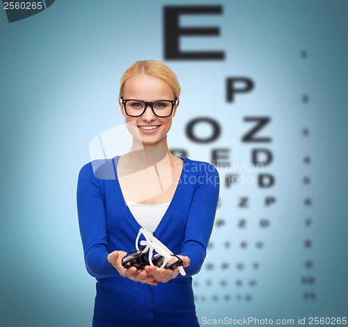 Image of smiling woman wearing and holding eyeglasses