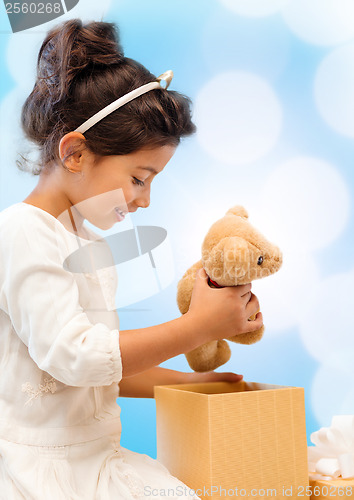 Image of happy child girl with gift box and teddy bear