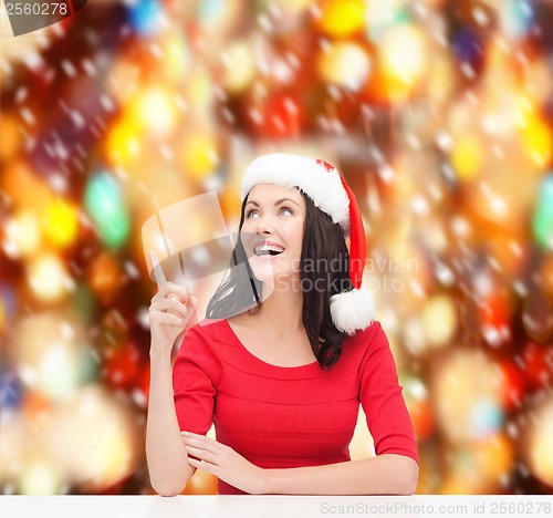 Image of woman in santa helper hat pointing to something