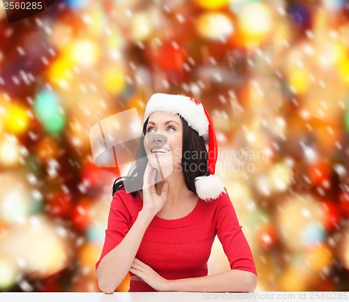 Image of surprised woman in santa helper hat looking up
