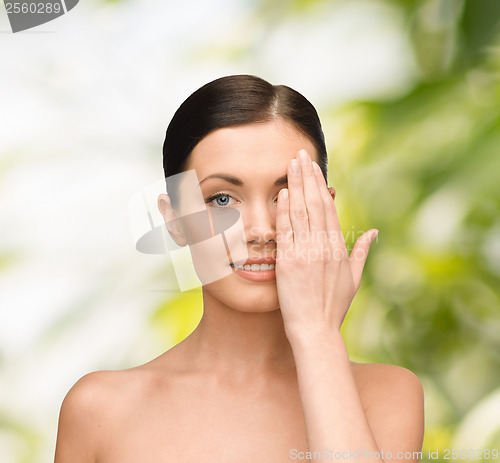 Image of smiling young woman covering face with hand