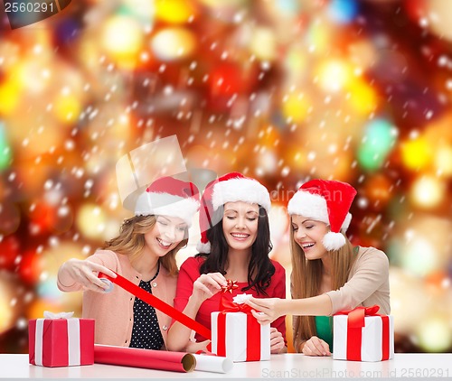 Image of smiling women in santa helper hats with gift boxes