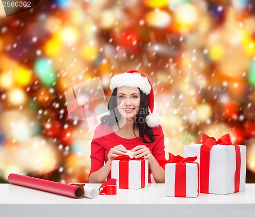 Image of woman in santa helper hat with many gift boxes