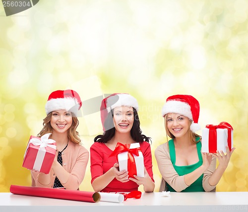 Image of smiling women in santa helper hats with gift boxes
