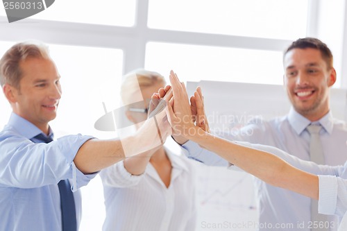 Image of happy business team giving high five in office