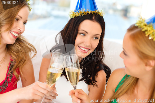 Image of three women wearing hats with champagne glasses