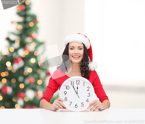 Image of woman in santa helper hat with clock showing 12