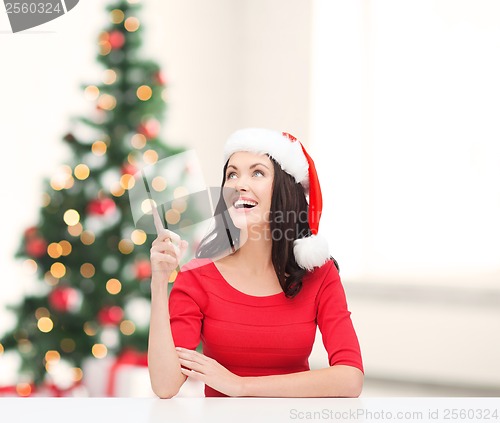 Image of woman in santa helper hat pointing to something