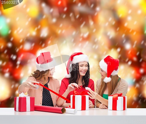 Image of smiling women in santa helper hats with gift boxes