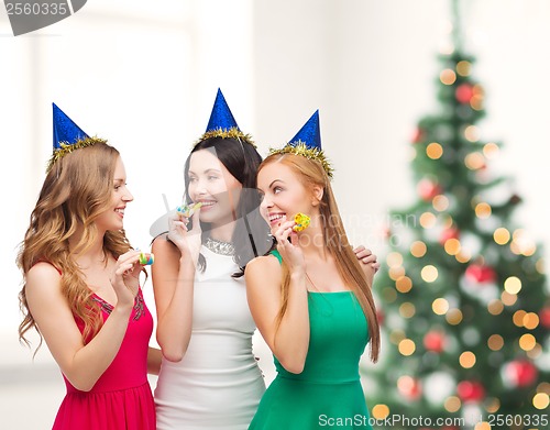 Image of three smiling women in hats blowing favor horns