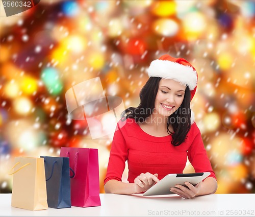 Image of smiling woman with shopping bags and tablet pc