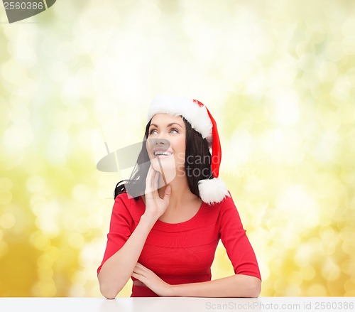 Image of surprised woman in santa helper hat looking up