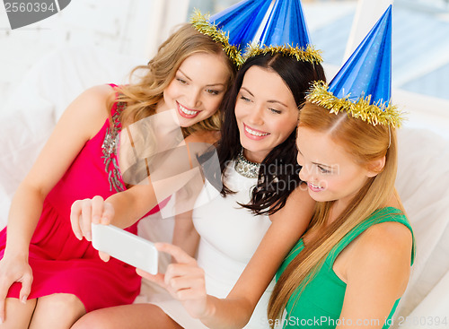 Image of three smiling women in hats having fun with camera