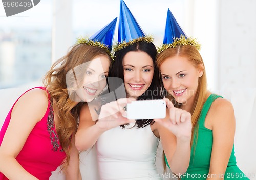 Image of three smiling women in hats having fun with camera