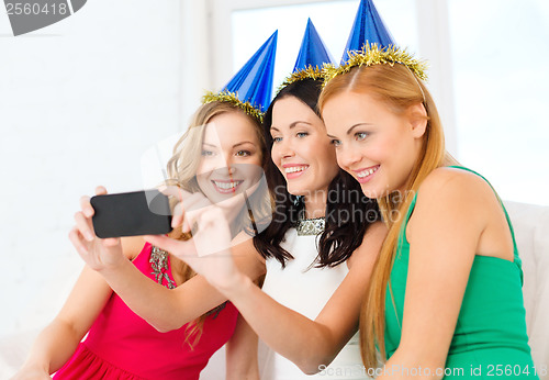 Image of three smiling women in hats having fun with camera