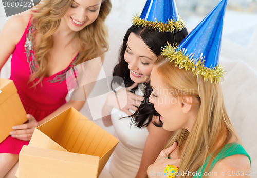 Image of three smiling women in blue hats with gift boxes