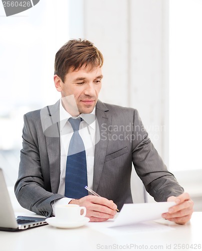 Image of businessman with laptop computer and documents