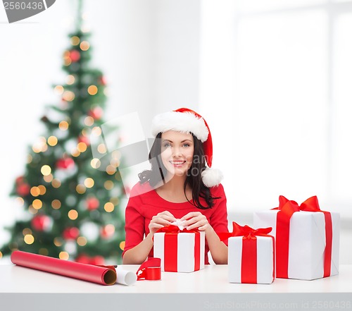 Image of woman in santa helper hat with many gift boxes