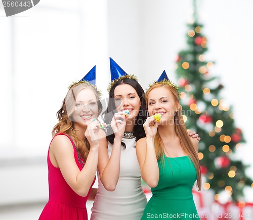 Image of three smiling women in hats blowing favor horns