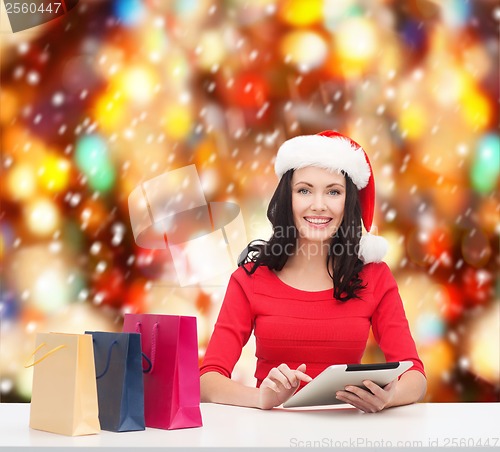 Image of smiling woman with shopping bags and tablet pc