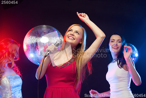 Image of three smiling women dancing and singing karaoke