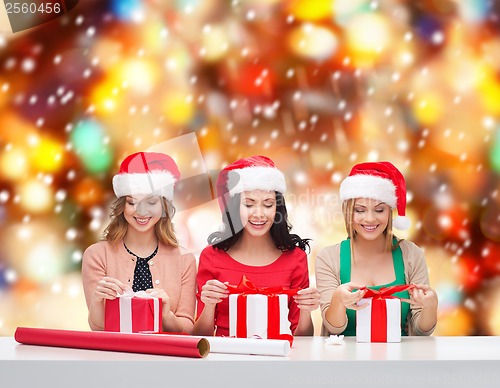 Image of smiling women in santa helper hats with gift boxes