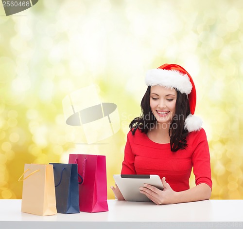 Image of smiling woman with shopping bags and tablet pc
